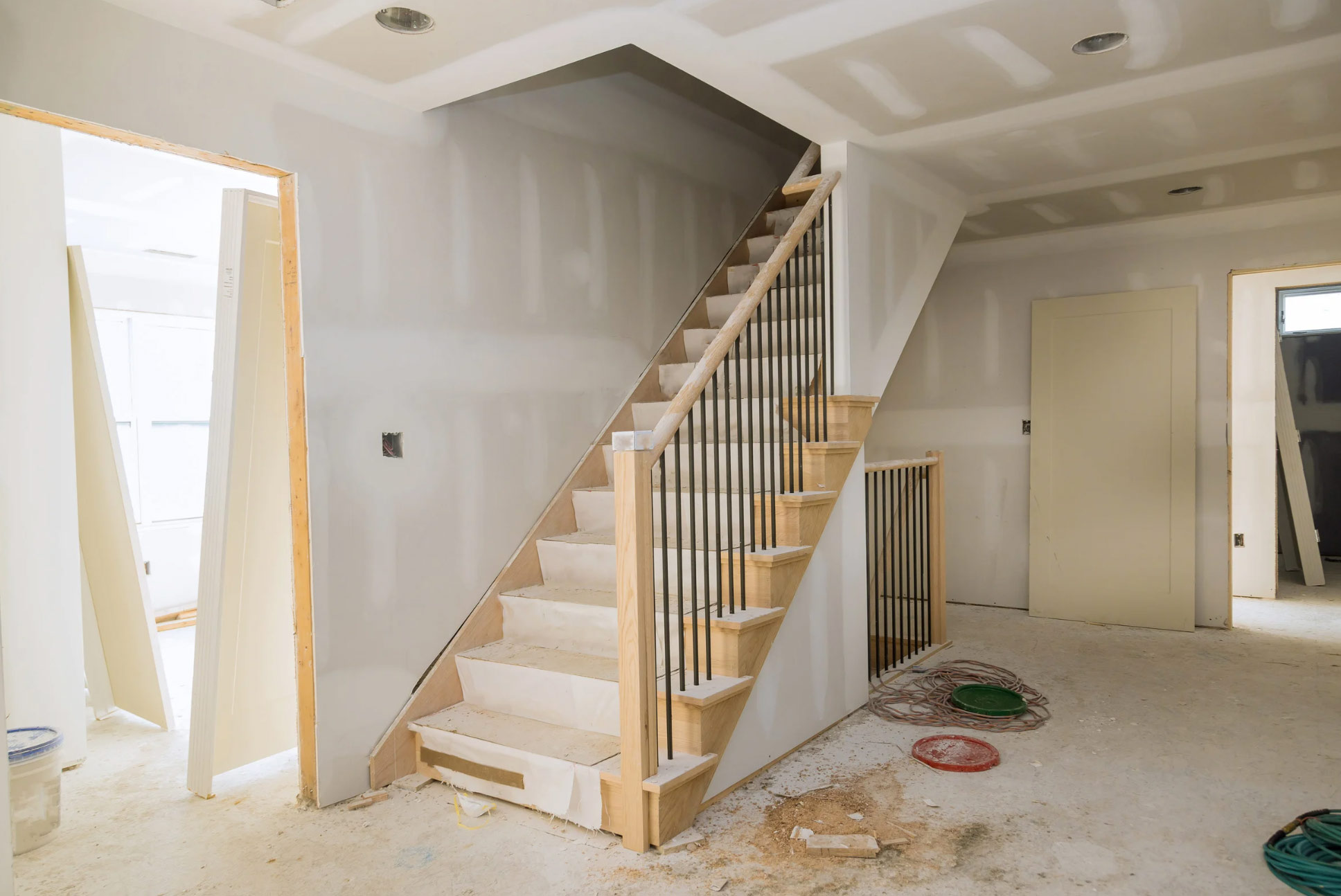 Unfinished staircase and walls in a house under construction with construction materials on the floor.