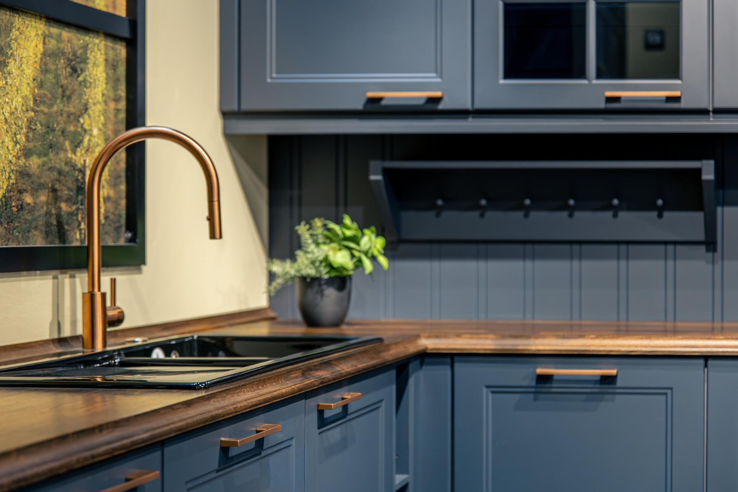 72798 Modern kitchen with dark blue cabinets, wood countertops, a bronze faucet, and a potted plant by the sink.